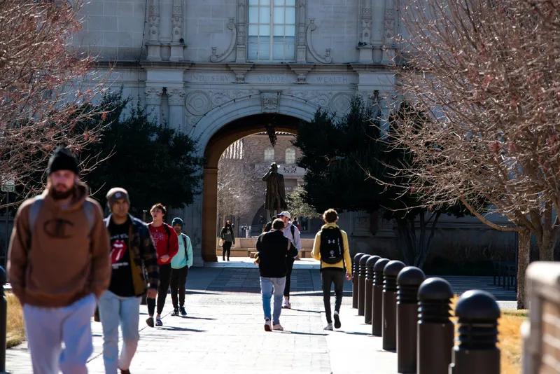 Estudiantes cruzando un arco en un campus universitario